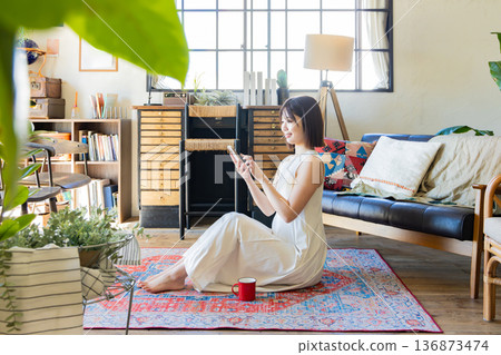 A woman in a dress sitting on a rug A woman in a dress sitting on a rug 136873474