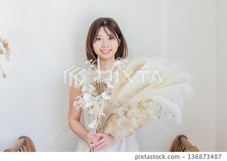 One-piece woman holding a bouquet of dried flowers One-piece woman holding a bouquet of dried flowers 136873487