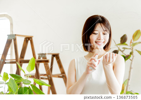 一位身穿洋裝的女子正在手腕上噴灑香水 136873505