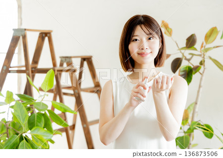 A woman in a dress spraying perfume on her wrist A woman in a dress spraying perfume on her wrist 136873506