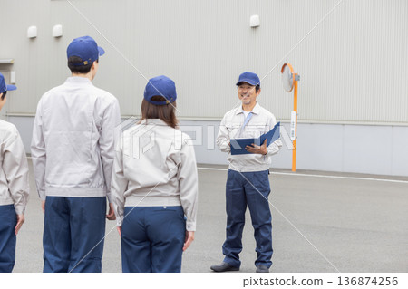 A group of workers having a morning meeting in front of the factory A group of workers having a morning meeting in front of the factory 136874256