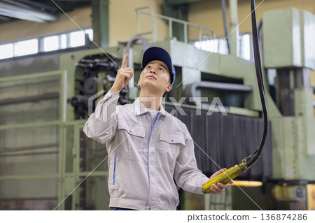 操作高架起重機/吊索控制器的工人 操作高架起重機/吊索控制器的工人 136874286