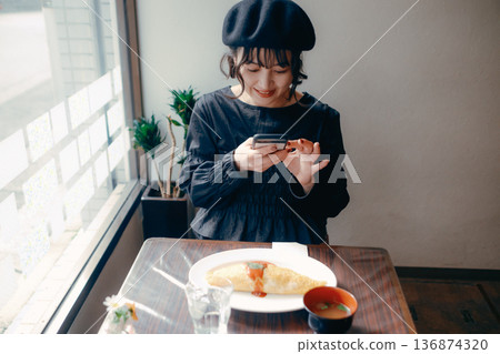 A Japanese woman in her 30s taking a photo of omurice with her smartphone 136874320