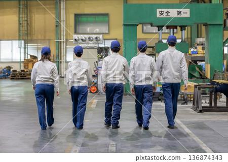 Rear view of a group of workers walking side by side in a factory Rear view of a group of workers walking side by side in a factory 136874343