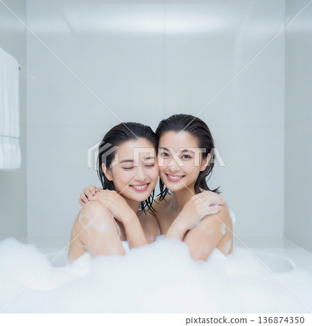 Two young women embracing each other in a bubble bath Two young women embracing each other in a bubble bath 136874350