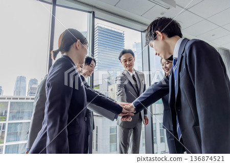 Business group standing in a circle with hands together Business group standing in a circle with hands together 136874521