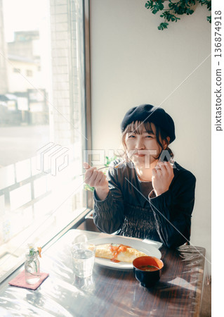 A Japanese woman in her 30s eating omurice, lunch scene 136874918
