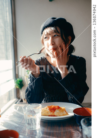 A Japanese woman in her 30s eating omurice, lunch scene 136874942