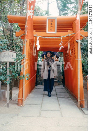 一位三十多歲的日本女子沿著鳥居行走。 一位三十多歲的日本女子沿著鳥居行走。 136875213