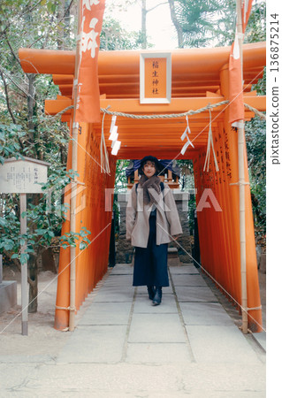 A Japanese woman in her 30s walking along the torii gate 136875214