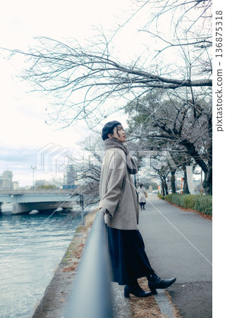 A Japanese woman in her 30s looking up at the sky along a river in winter A Japanese woman in her 30s looking up at the sky along a river in winter 136875318