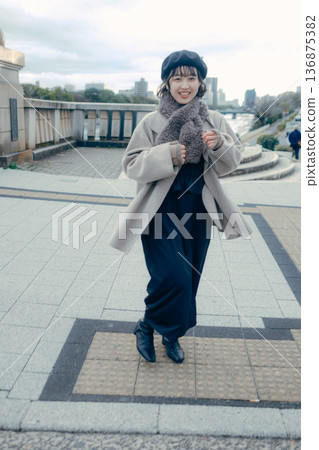一位三十多歲的日本女性微笑著走在冬日的城市街道上。 一位三十多歲的日本女性微笑著走在冬日的城市街道上。 136875382