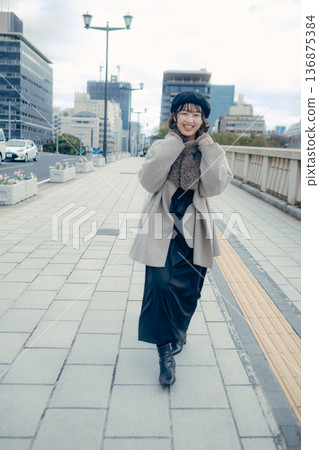 A smiling Japanese woman in her 30s walking through the city in winter A smiling Japanese woman in her 30s walking through the city in winter 136875384