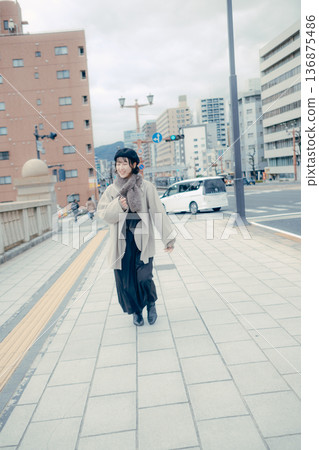 A smiling Japanese woman in her 30s walking through the city in winter A smiling Japanese woman in her 30s walking through the city in winter 136875486