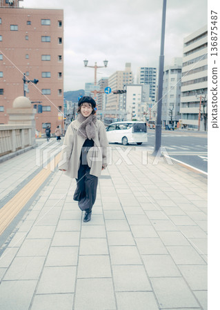 A smiling Japanese woman in her 30s walking through the city in winter A smiling Japanese woman in her 30s walking through the city in winter 136875487