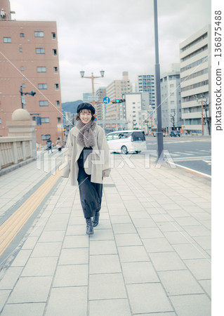 A smiling Japanese woman in her 30s walking through the city in winter 136875488