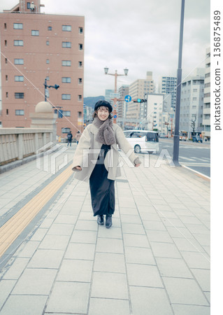 A smiling Japanese woman in her 30s walking through the city in winter A smiling Japanese woman in her 30s walking through the city in winter 136875489