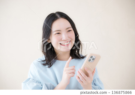 A smiling woman using a smartphone. Image of online use, reviews, and applications for services. A smiling woman using a smartphone. Image of online use, reviews, and applications for services. 136875866