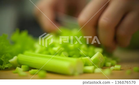 Close-up of a person slicing vibrant green vegetables on a cutting board, celebrating National Celery Month and healthy snacks 136876570