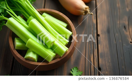 A bowl of fresh celery on a wooden table, showcasing a healthy snack option for wellness and detox during National Celery Month 136876584