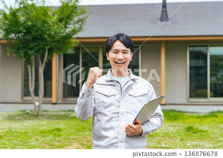 A male worker pumping his fist in front of a house A male worker pumping his fist in front of a house 136876678
