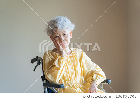 Senior woman sitting in a wheelchair and worried Senior woman sitting in a wheelchair and worried 136876703