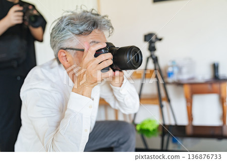 Senior male photographer taking pictures with a digital camera Senior male photographer taking pictures with a digital camera 136876733