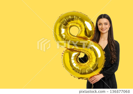 Woman holds a gold balloon in the shape of number 8 Woman holds a gold balloon in the shape of number 8 136877068
