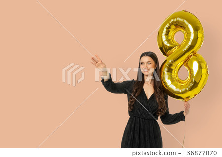 A young woman waves with a large number 8 balloon A young woman waves with a large number 8 balloon 136877070