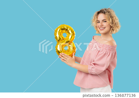 A girl holds a golden balloon shaped like number eight A girl holds a golden balloon shaped like number eight 136877136