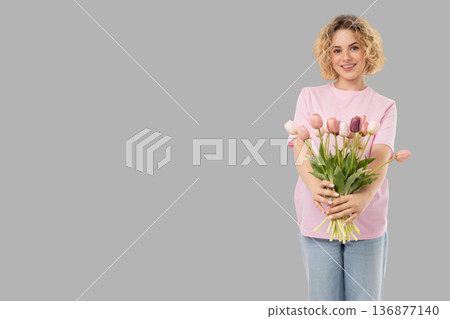 A woman holds a bouquet of tulips while smiling 136877140