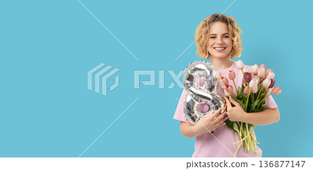 A woman holds flowers and a balloon while smiling A woman holds flowers and a balloon while smiling 136877147
