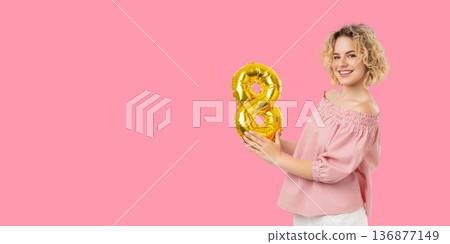 A woman smiles while holding a golden number balloon A woman smiles while holding a golden number balloon 136877149