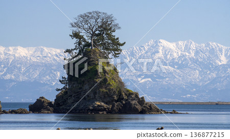 A spectacular view of the snow-capped Tateyama mountain range and Onnaiwa Rocks from Amaharashi Coast in winter, with blue skies 136877215