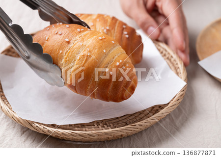 Salt bread (Shio pan) with sea salt flakes is picking up by tongs, Japanese bakery style 136877871