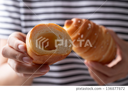 Salt bread (Shio pan) with sea salt flakes holding by woman hand and eating, Japanese bakery style Salt bread (Shio pan) with sea salt flakes holding by woman hand and eating, Japanese bakery style 136877872