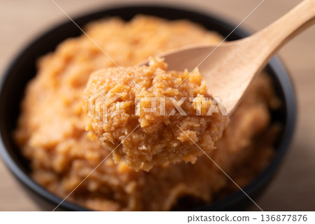 Scooping traditional Japanese miso paste from a black bowl with a wooden spoon Scooping traditional Japanese miso paste from a black bowl with a wooden spoon 136877876