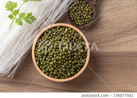 Mung beans seeds and dried glass noodles on a wooden table, raw ingredients for Thai vermicelli Mung beans seeds and dried glass noodles on a wooden table, raw ingredients for Thai vermicelli 136877881