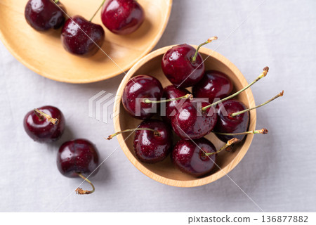 Fresh red cherries with water droplets in a wooden bowl on fabric background 136877882