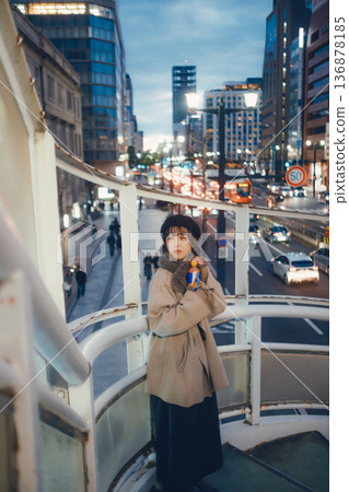一位三十多歲的日本女性在夜色下的城市裡手持一杯熱飲。 136878185