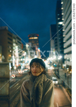 一位三十多歲的日本女性在夜晚站在城市街頭。 一位三十多歲的日本女性在夜晚站在城市街頭。 136878340