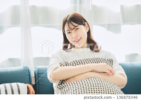 一位三十多歲的面帶微笑的女性在自然光下的客廳裡放鬆休息的肖像照 一位三十多歲的面帶微笑的女性在自然光下的客廳裡放鬆休息的肖像照 136878346