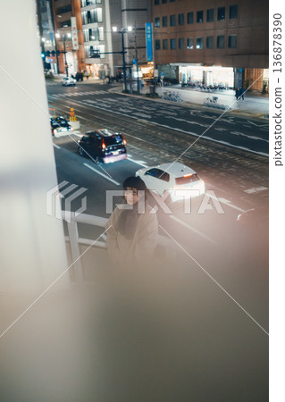 A Japanese woman standing on a pedestrian bridge at night A Japanese woman standing on a pedestrian bridge at night 136878390