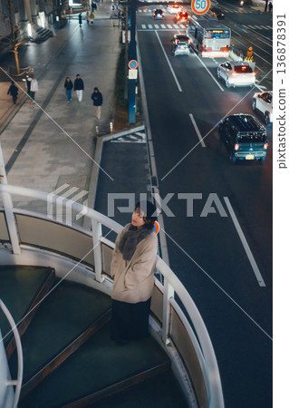 A Japanese woman standing on a pedestrian bridge at night A Japanese woman standing on a pedestrian bridge at night 136878391