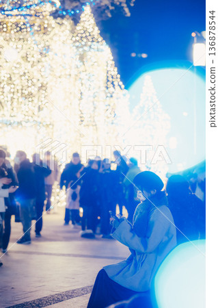A woman looking at her smartphone in front of illuminations 136878544