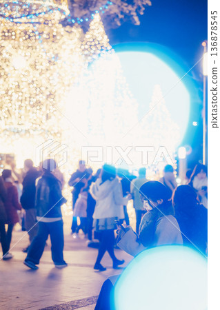 A woman looking at her smartphone in front of illuminations 136878545