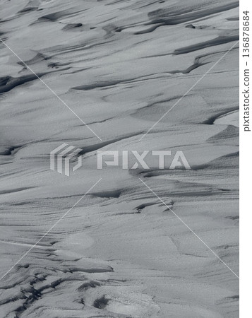 Wind-sculpted snow drifts and textured snow surface on a cold winter slope Wind-sculpted snow drifts and textured snow surface on a cold winter slope 136878684