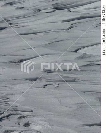 Wind-sculpted snowdrifts and textured winter snow surface with soft ripples and shadows 136878685