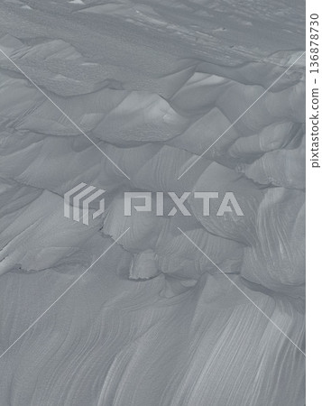 Aerial view of wind-sculpted gray sand dunes with rippled texture and abstract patterns Aerial view of wind-sculpted gray sand dunes with rippled texture and abstract patterns 136878730