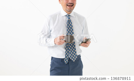 一位面帶微笑的商人,手裡拿著一杯咖啡 一位面帶微笑的商人,手裡拿著一杯咖啡 136878911